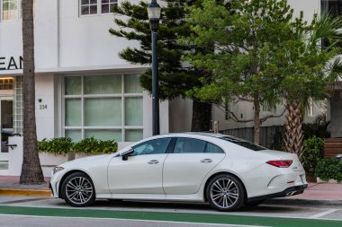 Miami Beach, Florida USA - 9 Haziran 2024 Miami plajında Porsche Taycan beyaz rengi. Ocean 'daki lüks araba porshche' si Miami plajına gidiyor. ön köşe görünümü