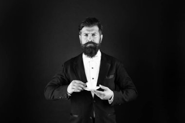 serious man in tuxedo bow tie with coffee cup. gentleman in formalwear drink coffee on black background.