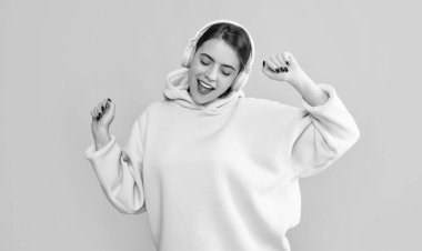 positive young girl listen music in headphones on yellow background.