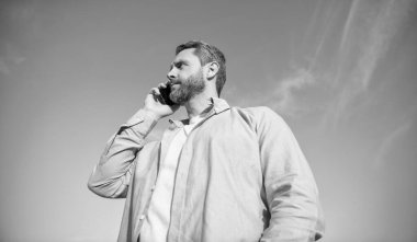 Tanrı bağlantısı. Telefonda erkek erkeğe konuşma. Adam akıllı telefondan konuşuyor. Gökyüzü arka planında insan iletişimi.