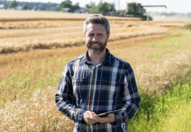 Tarlada tableti olan çiftçi tarımcı adam. Modern tarımın teknolojisi. Tarlada tabletle çalışan çiftçi. Tablet çekli İspanyol çiftçi. Ekin hasadı.