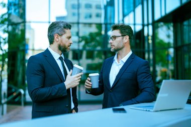 Çalışıyorum. İş adamları e-postaları kontrol ediyor. İş adamları dışarıda serbest çalışıyor. İnternette iş. Dizüstü bilgisayarda çalışan adamlar. Çevrimiçi çalışan iş adamları. Dizüstü bilgisayarlı iş adamları. Kahve molası.