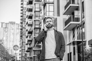 Şehir sokağında cep telefonuyla konuşan bir adam var. Adam cep telefonunu arıyor. Cep telefonundaki adamın fotoğrafı. Adamın dışarıda cep telefonu var..