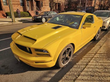 New York City, ABD - 18 Mart 2024: Ford Mustang GT coupe sarı açık hava, köşe manzaralı.