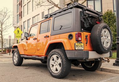 New York, ABD - 31 Mart 2024: 2012 Jeep Wrangler Sınırsız Sahra sarı arabası açık havada park edilmiş, nadir manzara.