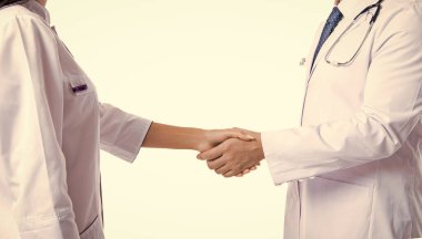 Doktor, hemşireyle tokalaşıyor. İki doktor beyazın üzerinde el sıkışıyor. Tokalaşma, hasta sağlığı konusunda anlaşma. Hastane takım çalışması işbirliği. Başarılı tedavi. Yakın çekim.