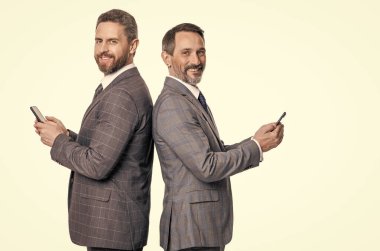 Mesajlaşan iki işadamı e-postaları kontrol ediyor. Telefondaki mesajları okuyan iş adamları beyazdan izole edilmiş. İş mesajlaşması. İnternet üzerinden iş mesajlaşması. Takım elbiseli iş adamları telefon kullanır. İleti adabı.