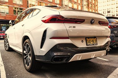 New York City, USA - March 15, 2024: BMW X6 modern white car parked outdoor, back side view. clipart