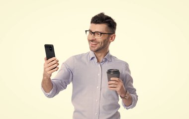 İş adamı iletişim için telefonu kullanıyor. Kahveli bir iş adamı beyazın üstüne izole edilmiş. Kahve molası. İş iletişimi. Adam iş konuşuyor. Telefon var. İletiyi temizle.