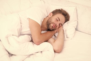 Uykulu adam beyaz yatak odasında uyuyor. Uyuyan genç adam uyuyor. Rahat bir yatakta huzur içinde dinleniyor. Kapalı gözlerle yalan söylemek. Derin erkek uykusu. Geceleri uyuyan bir adam. Sakin bir gece..