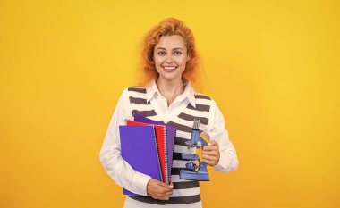 Mikroskobu sarı olan öğretmen. Kadınlar için biyoloji bilimi. Mikroskop araştırması. Okul biyoloji öğretmeni kadının elinde mikroskop var. Kadın biyoloji öğretmeni. Okula dönelim. Çalışmak için ekipman.