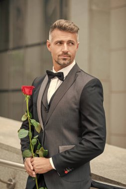 Nişan fikri. Yakışıklı smokinli adam nişanı kutluyor. Nişan için gül hediyeli bir adam.