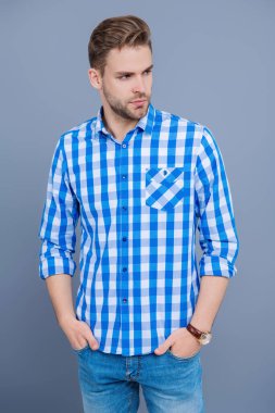 Sıradan tişörtlü bir adamın portresi. Tıraşsız adamın zarif portresi. Gri yolda izole edilmiş bir adam. Kareli gömlek giyen milenyum adamı. Milenyum erkeğinin gündelik tarzı. Sıradan şıklık..