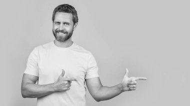 Reklam sunan adam sarı alana izole edilmiş, kopyala uzayı. Adam arka planda reklam sunuyor. Stüdyoda reklam sunan adam. Reklam sunan adamın fotoğrafı.