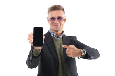 İş uygulamasının reklamı. Olgun iş adamı telefon ekranını sunuyor. İş adamı, telefonun beyazda izole olduğunu gösteriyor. Adam yeni iş telefonu uygulamasını gösteriyor. Ürünü sunuyorum. İşaret parmağı.