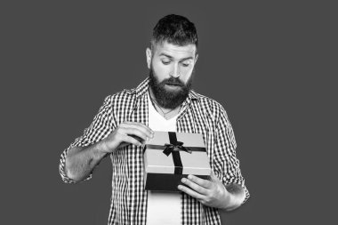 Meraklı, olgun, sakallı, gri arka planda mevcut kutusu olan bir adam..