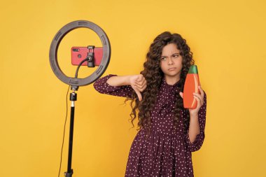 Uzun kıvırcık saçlı çocuk, blog şampuanı için video çekiyor. başparmak aşağı.