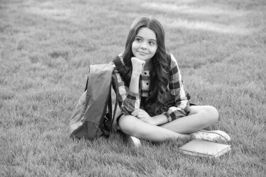 Thoughtful teenage girl sitting on grass after school, education. back to school. pupil at school time.