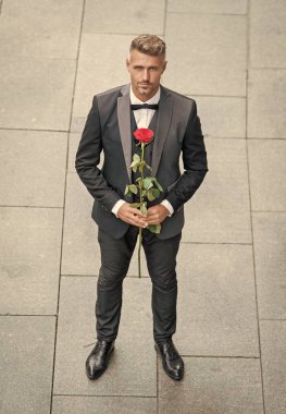 Smokinli yakışıklı adam. Dışarıda papyon giyen bir adam. Kırmızı güllü yakışıklı smokinli adam..