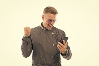 Mutlu gülümseyen başarılı iş adamı iş adamı yönetmeni mobil bahis kazananı akıllı telefonu kullanarak resmi palto stüdyosunda kazanan jest yaptı..