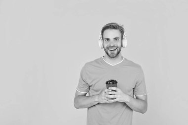 Okula dönüyorum. Kulaklıklı genç adam. Müzik aşığı. Müzik dinle. Kablosuz cihaz aksesuarı. Yeni teknoloji. Modern kulaklıklı, kahve fincanı olan mutlu bir adam. çevrimiçi eğitim.