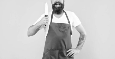 Happy man crop view holding cooks knife wearing red apron yellow background, cook.