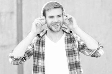 cheerful man listening music outdoor. man listening music outside. man listening music and wearing checkered shirt. photo of man listening music in headphones.