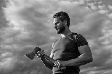 Baltalı adam. Zanaatkar adam baltayı tutar. Dramatik arka planda vahşi bir adam.