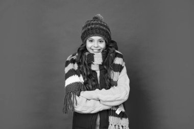 Kırmızı arka planda örülü kış şapkası ve atkısı olan mutlu genç kız, sezon modası..