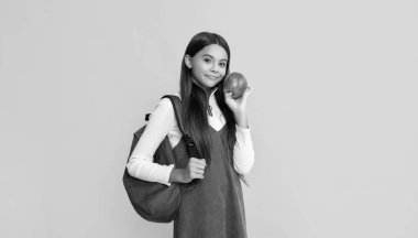 Sırt çantalı çocuk gülüşü ve sarı arkaplanlı elma.