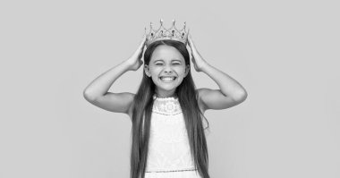 glad teen girl in crown on yellow background.