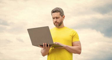 man working online on computer on sky background.