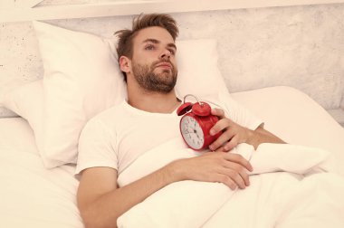 Uykulu adam çalar saati kapatıyor. Erken kalkmak. Uyanma ve kalkma vakti geldi. Sabah uyanması. Yatakta yatarken elinde çalar saatle uyuyan adam. Sabah uyanışı. Temel sabah hatırlatıcısı.