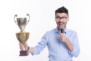 Şampiyon kupa ve mikrofon tutan başarılı bir iş adamı. Ticari başarı. İş başarısı. İş adamı zaferi beyazların izole edildiği bir törenle kutluyor. Şaşırdın mı?.