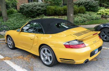 Chicago, Illinois - September 29, 2024: Porsche 911 turbo Carrera S yellow color. Porsche 911 turbo Carrera S parked the road. front view clipart