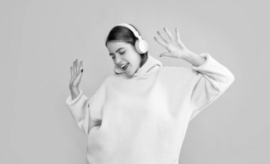 Neşeli genç kız sarı arka planda kulaklıkla müzik dinliyor..