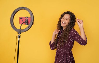 Mutlu çocuk uzun kıvırcık saçlarıyla blogda video çekerken iyi eğlenceler..