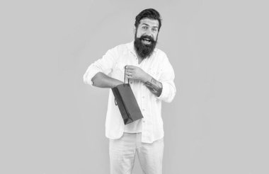 Stüdyoda gülümseyen adam indirimli alışveriş yaparken çekilmiş. Sarı arka planda izole edilmiş bir adam için iyi indirim. Alış veriş yapan adam indirim yapıyor. Sakallı adam reklam indirimi yapıyor..