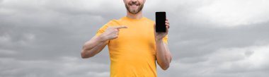 cropped view of man presenting screen of smartphone with copy space. pointing finger.