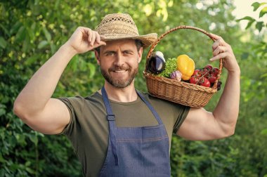 Saman şapkalı mutlu adam içi sebze dolu sepeti tutuyor..