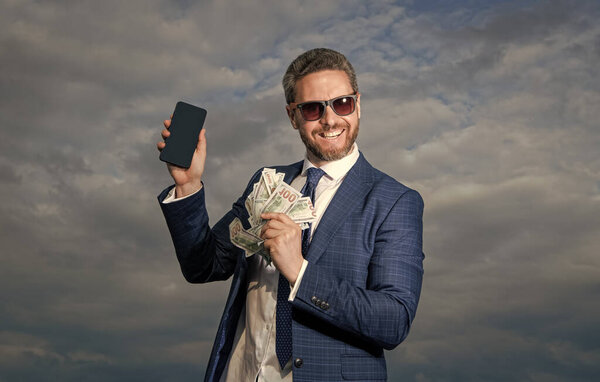 photo of positive betting man with lottery money. betting man with lottery money on sky background. betting man with lottery money outdoor. betting man with lottery money hold phone.