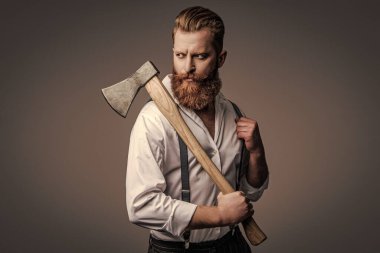 Sakallı adam, baltayı tut. Saç ve sakal bakımı. Yakışıklı, sakallı, vahşi adam. Sakal şekillendirme. Bıyıklı, Kafkas bir hippi. Sakallı adam gri yolda izole edilmiş. Moda ve Eğilimler.