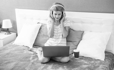 positive woman blogger with coffee in headphones. blogger woman at home. blogger woman work with laptop. clipart