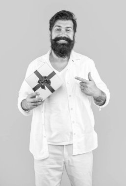 Adam arka planda satılık bir hediye sunuyor. Bir adamın fotoğrafı hediye paketi sunuyor. Sakallı adam sarı üzerine izole edilmiş bir hediye sunuyor. Stüdyoda satış hediyesi..