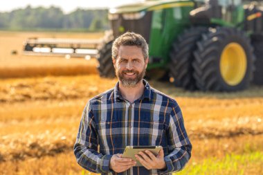 Tablet çekli İspanyol çiftçi. Ekin hasadı. Tarlada tableti olan çiftçi tarımcı adam. Modern tarımın teknolojisi. Tarlada tabletle çalışan çiftçi. Altın hasat alanları.
