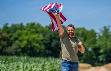 Amerikan bayrağı ve çiftçi adam, hasat zamanı. ABD bayrağı. Bağımsızlık Günü. Sahadaki adam. Sahada Amerikan bayrağı taşıyan vatansever adam. Amerika 'nın Bağımsızlık Günü. 4 Temmuz. İşçi bayramı. Boşluğu kopyala.