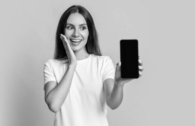 Ürün teklifi. Reklam sunumu kopyalama alanı. Telefon ekranı sunan bir kadın. Sarıda izole akıllı telefon gösteren bir kadın. Telefon uygulaması gösteren bir kadın. Sunulan günlük.