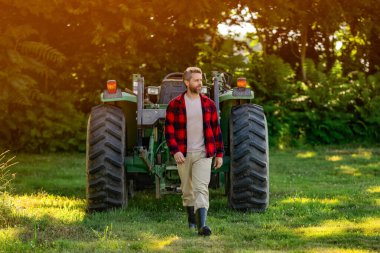 Traktörde olgun bir adam var. Traktör sürücüsü. Tarım ve saha işleri. Tarladaki çiftçi dışarıda traktörle sakız botu giyiyor. Ekin hasadı. Tarım tarım tarım teknolojisi. Hasat makineli çiftçi.