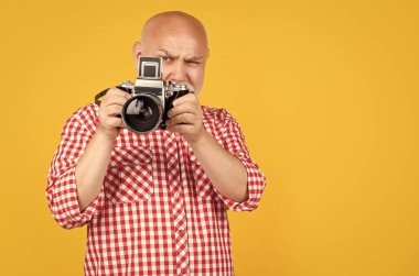 cheerful senior man with retro photo camera on yellow baqckground. clipart