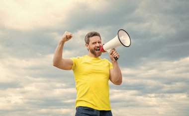 Sarı gömlekli adam arka planda megafonla bağırıyor. ses.
